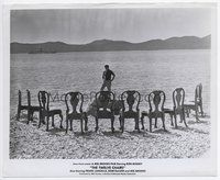 5j596 TWELVE CHAIRS 8x10 still '70 director Mel Brooks on beach standing on rock facing ten chairs!