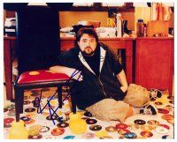 3a326 KEVIN SMITH signed color 8x10 REPRO still '00s great close up by Mickey Mouse chair & CDs!