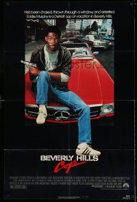 8a168 BEVERLY HILLS COP 1sh '84 great image of cop Eddie Murphy with gun sitting on Mercedes!