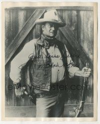 7x1294 JOHN WAYNE signed 8x10 REPRO still '70s c/u with rifle in one hand & six-shooter in the other