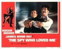 3e843 SPY WHO LOVED ME LC #2 '77 Roger Moore as James Bond squeezed by giant Richard Kiel as Jaws!