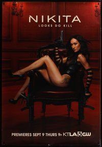 3z229 NIKITA DS bus stop '10 full-length image of sexy Maggie Q seated in skimpy black outfit!