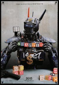 7g123 CHAPPIE teaser DS 1sh '15 close up image of the robot with toy blocks, huge necklace and gun!