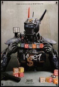 5g157 CHAPPIE teaser DS 1sh '15 close up image of the robot with toy blocks, huge necklace and gun!
