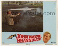 6j077 BRANNIGAN LC #6 '75 angry detective John Wayne fighting gun while sitting in the dirt!