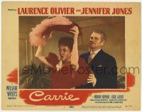 8f495 CARRIE LC #1 '52 Laurence Olivier stands behind Jennifer Jones as she puts on hat!